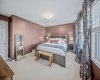 Custom designer drapery and rich, moody paint give the oversized primary retreat a warm and elevated feel.
