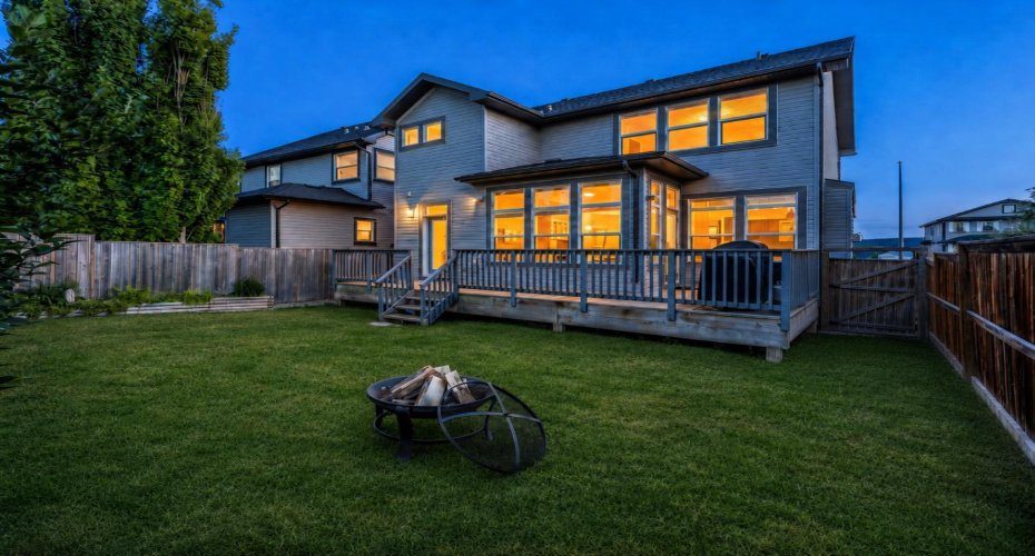 Twilight backyard view with warm interior light creating an inviting evening atmosphere.
