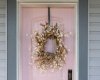 A soft pink front door adds warmth and personality to the covered entry.